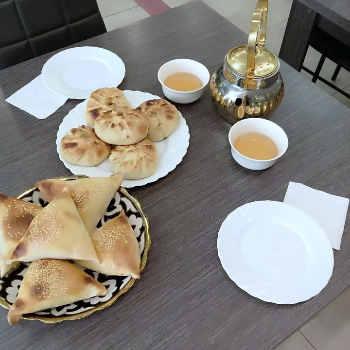 Самса с кунжутом и печёные пирожки, рядом чайник и пиалы с чаем